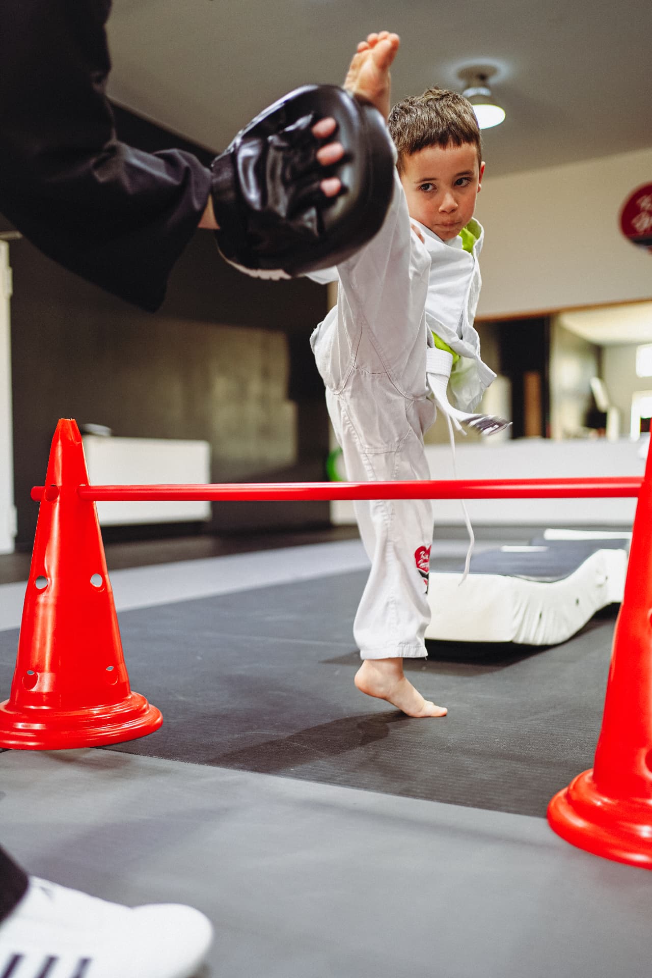 Junge führt konzentriert einen hohen Kick im KAMPFKUNST HERZ® Dojo