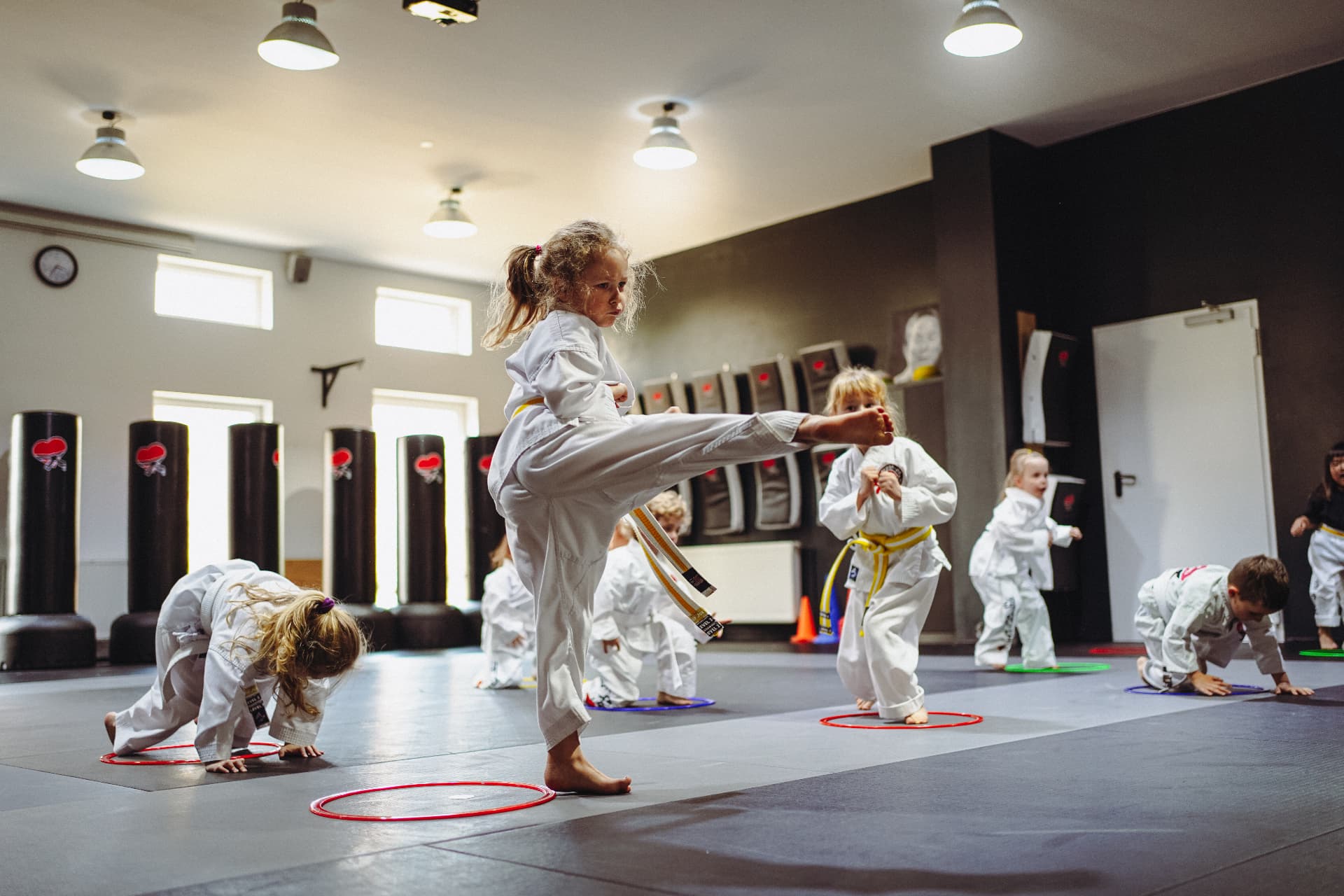 Kleine Kinder üben in farbigen Reifen auf der Matte im KAMPFKUNST HERZ® Dojo